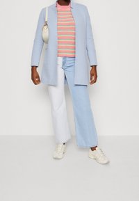 Světle modrý kabát, svetr s růžovými pruhy, bílé a světle modré džíny a krémové tenisky. Obsahuje malou krémovou kabelku.