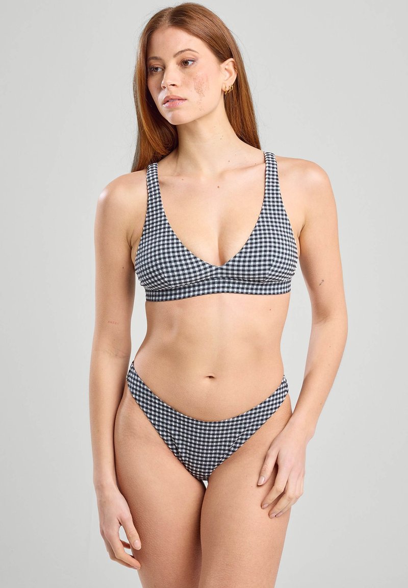 Ensemble de bikini à motif vichy noir et blanc, comprenant un haut à décolleté en V profond avec des bretelles larges et un bas taille basse avec une couverture minimale. Texture lisse.