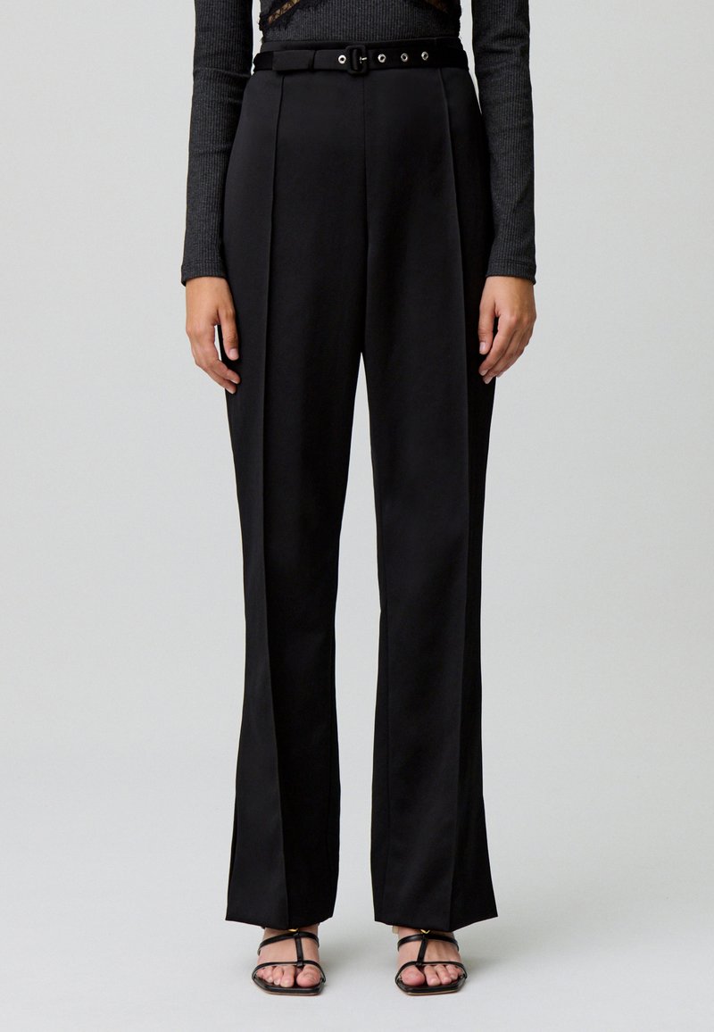 Pantaloni neri a vita alta con design a gamba dritta, caratterizzati da pieghe sartoriali, una cintura con fibbia regolabile e una texture liscia.