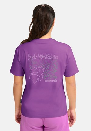 T-shirt violet à manches courtes arborant le texte "Jack Wolfskin", une empreinte de patte et des motifs abstraits verts au dos. Tissu en coton doux.