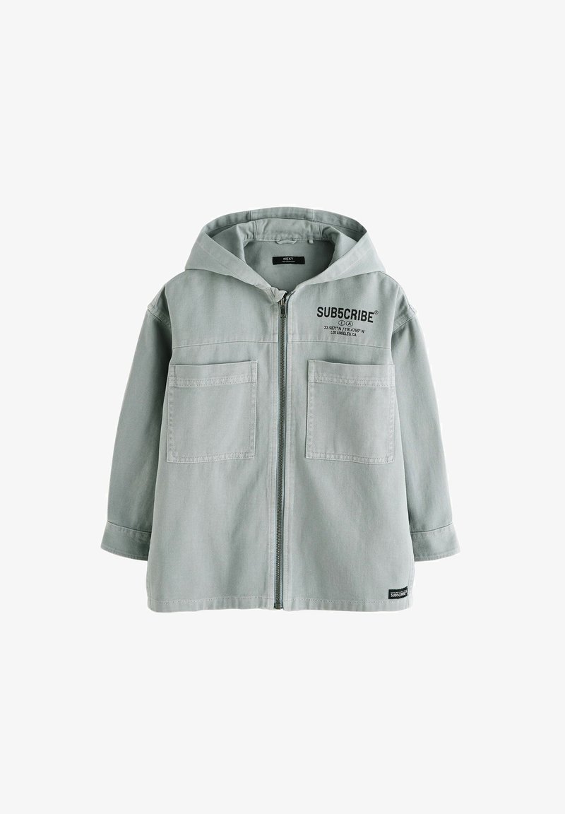 Veste à capuche gris clair avec fermeture éclair à l'avant, deux grandes poches sur la poitrine et texte noir "SUB5CRIBE" sur le côté supérieur gauche.