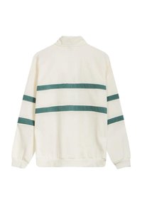 Sudadera de color crema claro con un cuello alto, que presenta tres franjas horizontales en color teal en la parte posterior y puños y dobladillo acanalados.