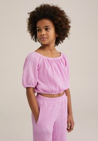Top corto texturizzato rosa con maniche a sbuffo abbinato a pantaloni coordinati. Il tessuto è stropicciato, creando una vestibilità morbida e comoda.