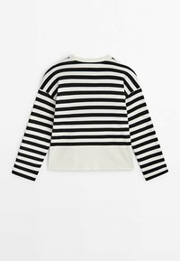 Pitkähihaisen mustavalkoisesti raidallisen paidan, jonka alaosa on kiinteää valkoista, esittely tasaisena, takapuoli näkyvissä.