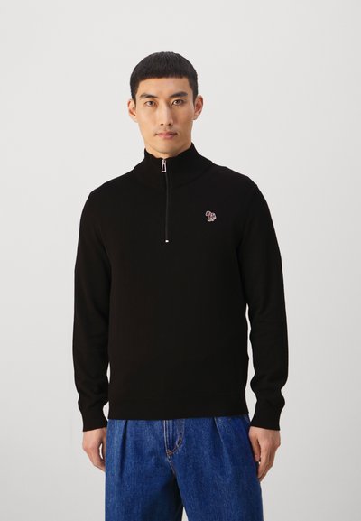 Fekete zipzáras pulóver bordás gallérral, a mellkason egy kicsi színes logóval. Simaságot sugalló kötött alapanyagból készült.