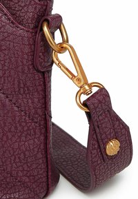 Burgundská umělá kožená taška s námi zlatými klipy a kováním. Texturovaný povrch se znatelným šitím a detailem loga.