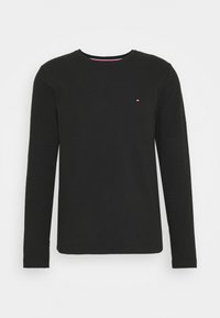 Schwarzes Langarm-T-Shirt aus strukturiertem Stoff; verfügt über einen Rundhalsausschnitt und ein kleines Logo in Rot, Weiß und Blau auf der Brust.