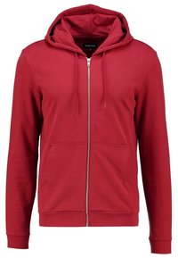Sudadera roja con cremallera hecha de tela suave; cuenta con una capucha, dos bolsillos frontales y puños acanalados. Textura suave y diseño casual.