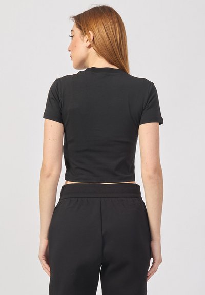 T-shirt nera corta con maniche corte, realizzata in materiale morbido, caratterizzata da un design semplice e un collo pulito. Indossata con pantaloni sportivi neri.