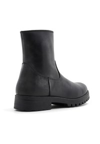 Botín negro de cuero hasta el tobillo con un acabado suave, puntera redondeada y suela de goma resistente. Presenta un minimalismo en las costuras y un diseño sencillo.