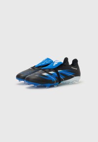 Schwarz-blaue Fußballschuhe mit einem eleganten Design, das ein auffälliges Logo und Stollen für Traktion aufweist, vor einem einfarbigen Hintergrund präsentiert.