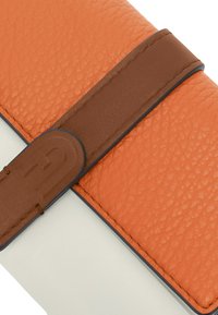 Zweifarbige Brieftasche mit einem oberen Abschnitt aus orangefarbenem, genarbtem Leder und einem glatten weißen unteren Abschnitt. Verfügt über einen braunen Ledertragegurt und runde Hardware-Details.