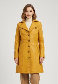 Yellow leather coat with large collar, front buttons, and side pockets. Features tailored seams and fitted silhouette. Smooth texture.