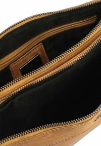 Interno di un portafoglio in pelle gialla con due scomparti con zip, foderato in nero e cuciture visibili lungo i bordi.