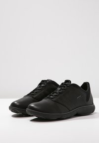 Black leather sneakers with a smooth finish, lace-up design, cushioned sole, and side accents. Geox logo displayed on the side.