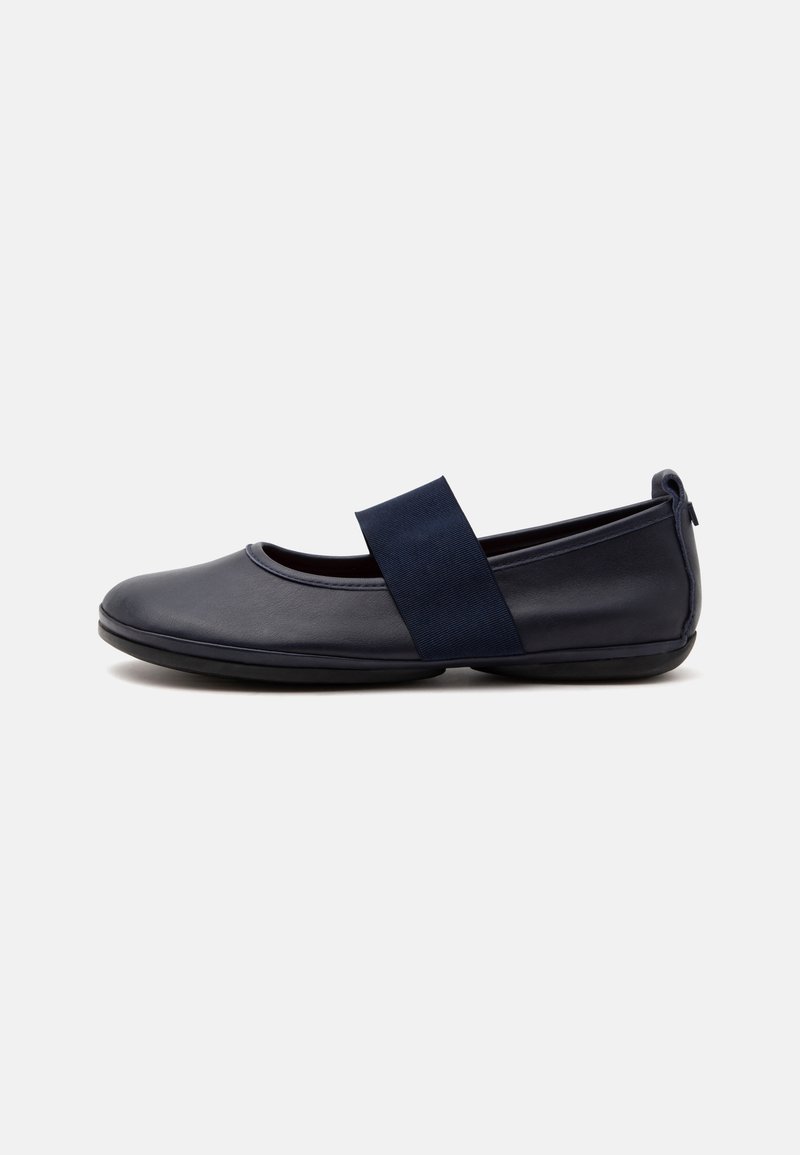 Chaussure plate en cuir bleu marine avec bout arrondi et large bride élastique sur le dessus, présentée de profil sur un fond clair.