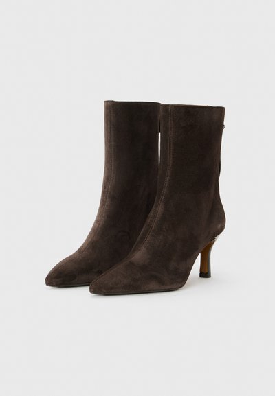 Ruske nubuk ankle boots z ostro konico in tankim peto. Gladka tekstura, prilegajoča zasnova in zadrga na hrbtni strani.