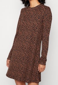 Robe à imprimé léopard marron avec des manches longues, un col rond et une coupe décontractée. Tissu doux avec une texture lisse.