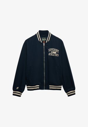 Granatowa kurtka bomberka z kremowymi paskami na kołnierzu i mankietach. Na piersi haft z napisem "Superdry Athletics" oraz dwie boczne kieszenie.