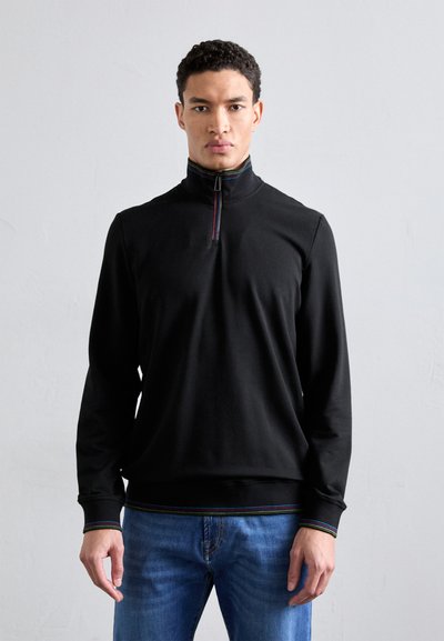 Černý pulovr s límcem na půl zip, který má barevnou pruhovanou linku podél límce a spodního lemu. Hladký materiál a dlouhé rukávy.