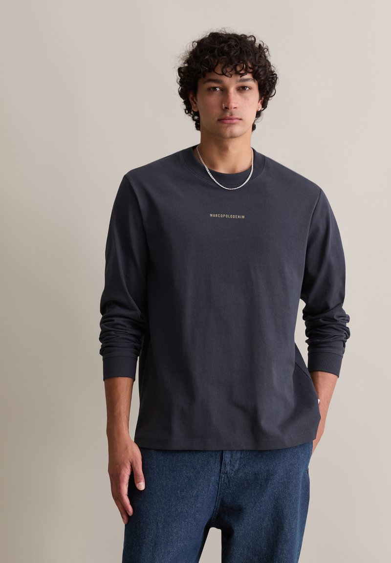 Koszula z długim rękawem w ciemnoszarym kolorze, wykonana z bawełny, z okrągłym dekoltem i ściągaczami na rękawach. Na piersi znajduje się napis "MARCOPOLODENIM" w kolorze złotym.