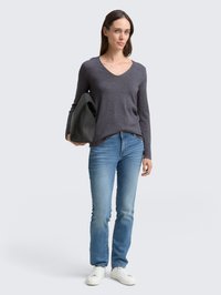 Camiseta gris de manga larga y escote en V, jeans azules de pierna recta, zapatillas blancas y un bolso tote negro. Diseño simple con textura suave.