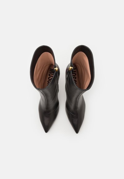 Black leather ankle boots with pointed toes, smooth texture, and a side zipper featuring gold hardware. Interior has beige lining.