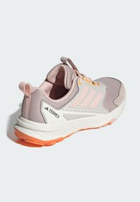 Pink and gray athletic shoe with mesh upper, white sole, orange accents, and three-striped design. Includes a pull tab at the heel.