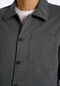 Kolsvart knapp-up skjorta i texturerad tyg, med en bröstficka och klassisk krage, samt svarta knappar.