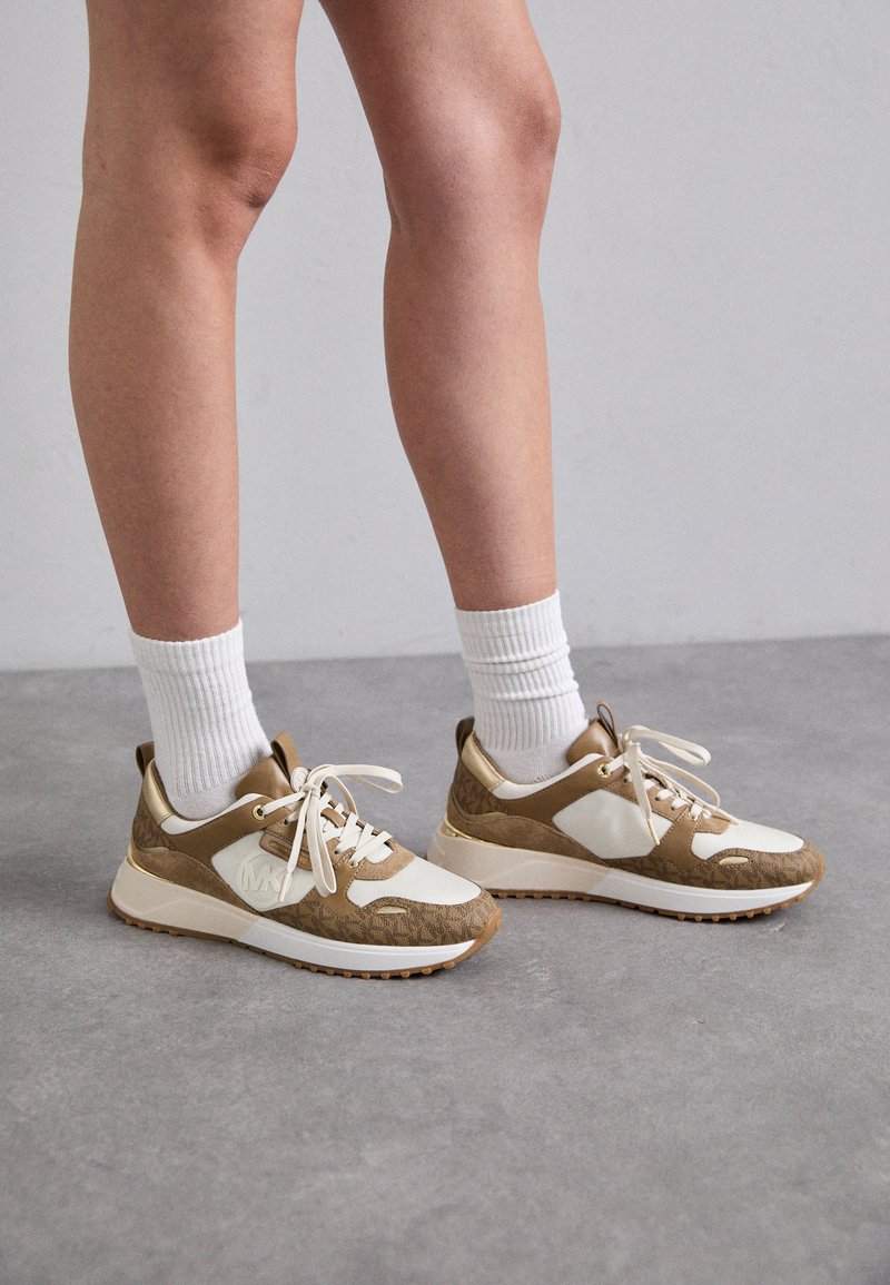 Brune og kremfargede sneakers med teksturert design, med hvite snørebånd, polstret krage og gummisåle med en subtil logo-detalj.