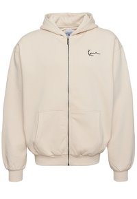 Beige rits-hals trui van zachte stof. Heeft een voorzichtingsrits, twee zakken en een geborduurd logo op de linkerborst.