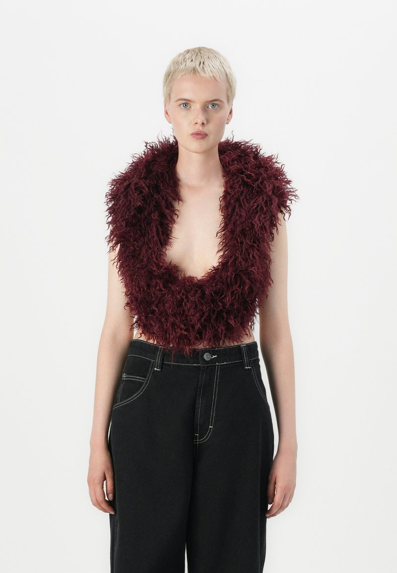 Burgundský faux fur crop top s širokým výstřihem, doplněný vysokým černým kalhotami s kontrastním švem.