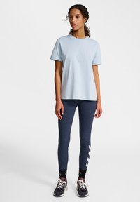 Ljusblå bomull T-shirt med rundad halsringning. Kombinerad med mörkblå leggings med ett vitt chevronmönster på sidan. Avslappnade sneakers.