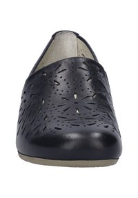 Chaussure noire en cuir à enfiler avec des motifs floraux découpés au laser, bout arrondi et semelle de couleur claire. Présente une texture lisse et un design minimaliste.
