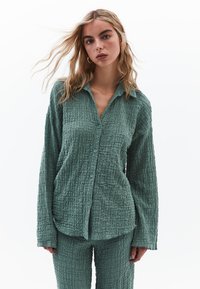 Texturovaná světle zelená košile s dlouhým rukávem a odpovídající kalhoty s knoflíky, s designem z mačkané látky pro uvolněný střih.
