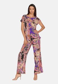 Gepatterneerde outfit met korte mouwen, paarse basis met ingewikkelde paisley-ontwerpen in roze, beige en zwart, gecombineerd met wijde broek.