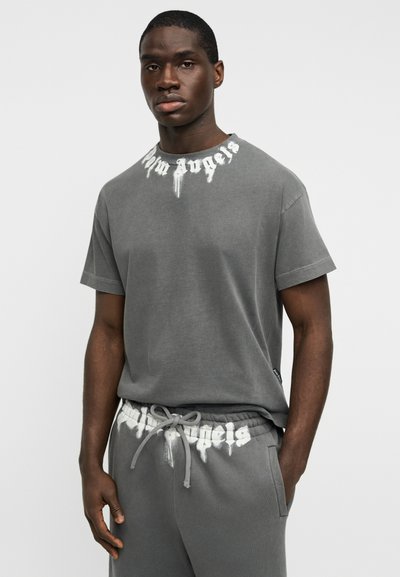 Γκρι βαμβακερό t-shirt με ένα χαρακτηριστικό λευκό εκτυπωμένο λογότυπο γύρω από το λαιμό. Το σχέδιο έχει άνετη εφαρμογή και κοντά μανίκια.