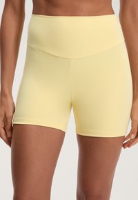 Rumene visoko pasne športne kratke hlače iz gladke, raztegljive tkanine. Imajo minimalne šive in prilegajočo se zasnovo za enostavno gibanje.