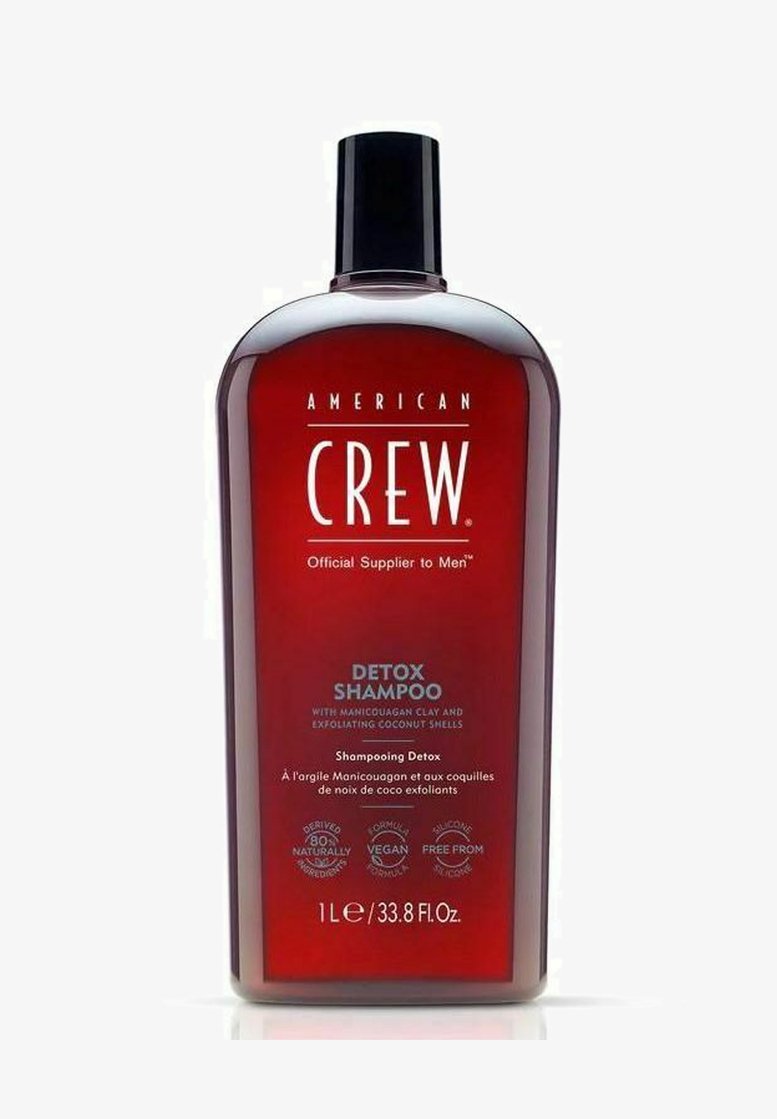 Rode plastic fles met een zwarte flip-top dop, gelabeld "DETOX SHAMPOO," bevat 1 liter shampoo met details over een veganistisch en siliconevrij formule.