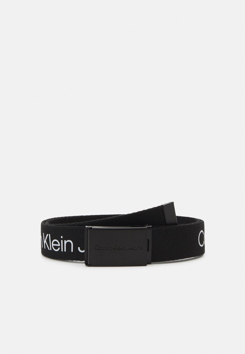 Zwarte stoffen riem met een metalen gesp, met een patroon van witte "Calvin Klein Jeans"-tekst langs de band. Textuur oppervlak.