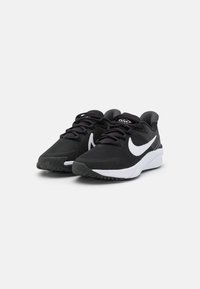 Zapatos deportivos negros con parte superior texturizada, que presentan un logo de Nike en blanco, cordones negros y una suela de goma diseñada para ofrecer tracción.