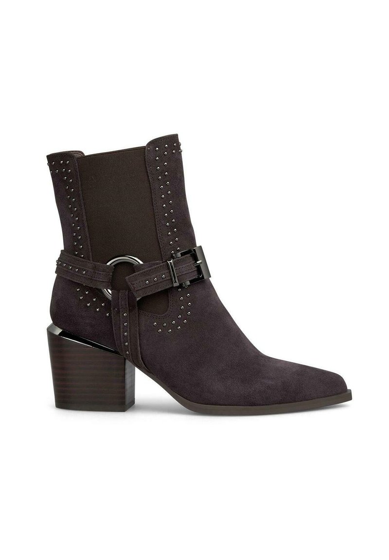Botín de ante marrón hasta el tobillo con punta afilada, paneles laterales elásticos, detalles de tachuelas y una hebilla decorativa. Presenta un tacón ancho.