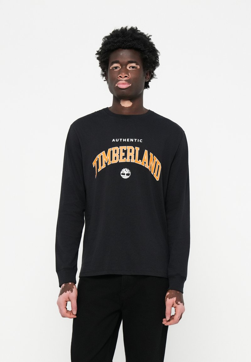 Schwarzes Langarmshirt mit "AUTHENTIC TIMBERLAND" in Orange, hat einen runden Halsausschnitt und besteht aus einem glatten Baumwollmaterial.
