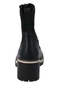 Botín negro con parte inferior de cuero texturizado, parte superior de tela suave y tacón grueso. Presenta una suela clara en contraste y cremallera en la parte trasera.