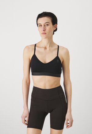Black sports bra with thin straps and a v-neck design, paired with high-waisted, dark brown bike shorts. Smooth fabric with minimal detailing.