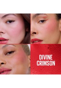 Trois femmes avec un maquillage cramoisi sur les joues et les lèvres, gros plan sur les visages ; fond rouge texturé avec le texte "DIVINE CRIMSON" en lettres blanches.