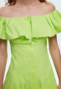 Vestido verde lima de hombros al descubierto con escote con volantes, que presenta un corsé ajustado, cinco botones en la parte delantera y falda plisada.