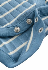 Tissu en tricot bleu avec un motif à carreaux blanc, comportant des boutons-pression en argent au niveau du col, une texture douce et des bords côtelés.