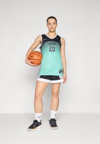 Giocatore di basket che indossa una maglia con degradé nero e acquamarina con il numero 20, pantaloni corti neri e sneakers nere, mentre tiene un pallone da basket arancione.