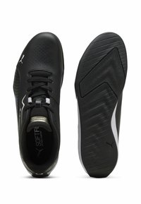 Baskets noires à lacets avec embout perforé, col rembourré, semelle texturée et logo Puma blanc sur la tige et la semelle, vues de dessus et de dessous.